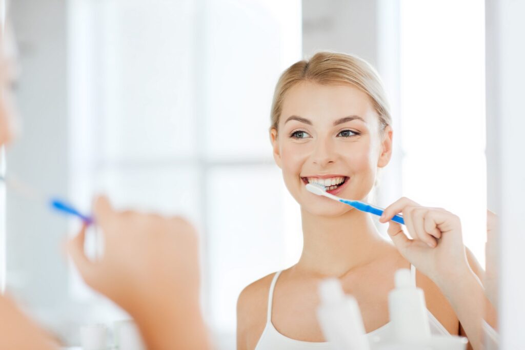 woman with toothbrush cleaning teeth at bathroom